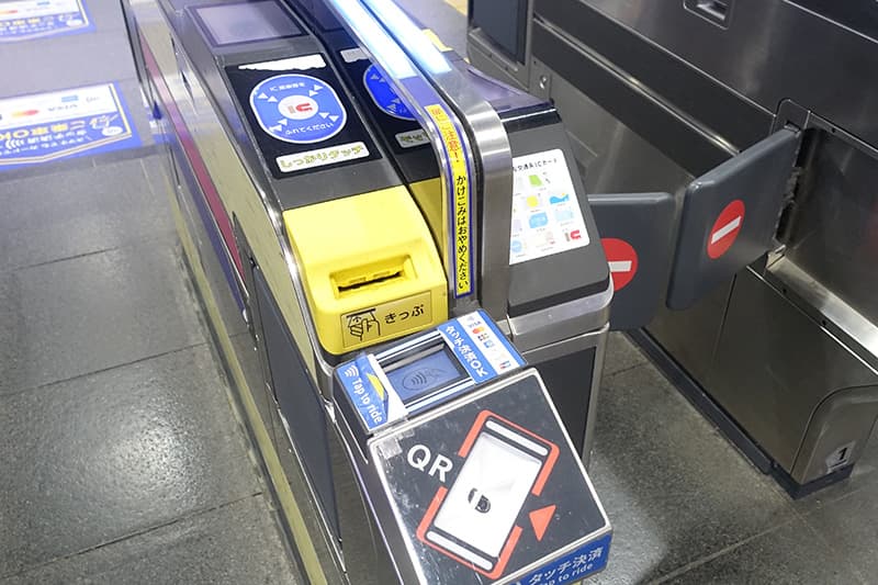 京王電鉄の改札に入場券を入れる